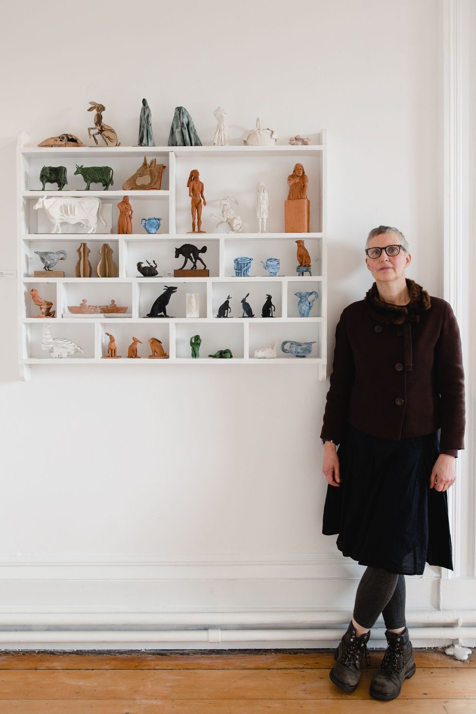 Marjan Wouda standing beside a shelf with her sculpture pieces on display at The Whitaker. Photo by Christina Davies, Fish 2 Photography.
