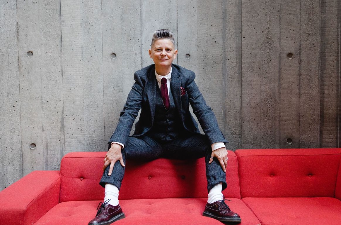 Joelle Taylor seated on the back of a red sofa at the South Bank Centre. Image: Christina Davies, Fish2Photo.