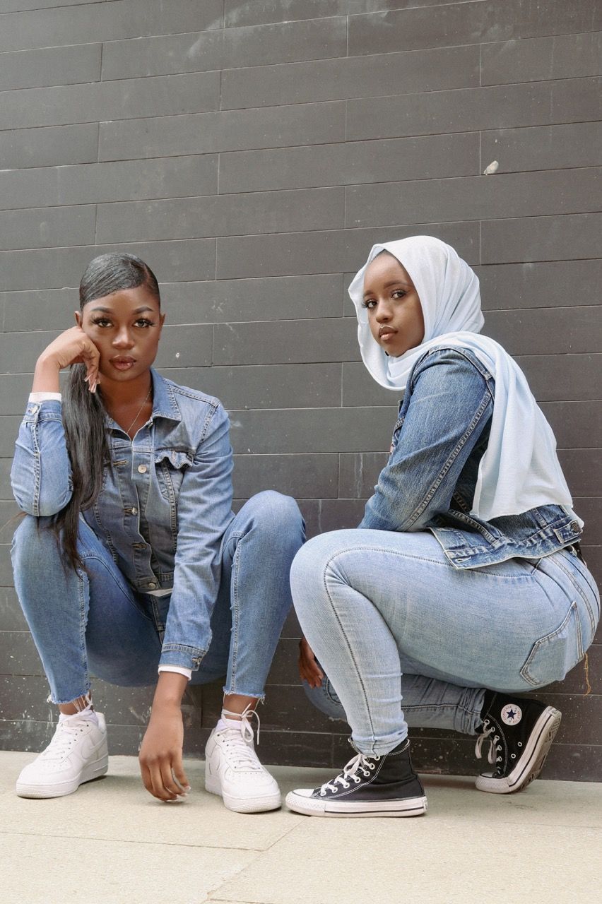 Two black women wearing denim kneeling on the ground facing camera, as part of the Woke Denim Project by Tiwirayi Ndoro