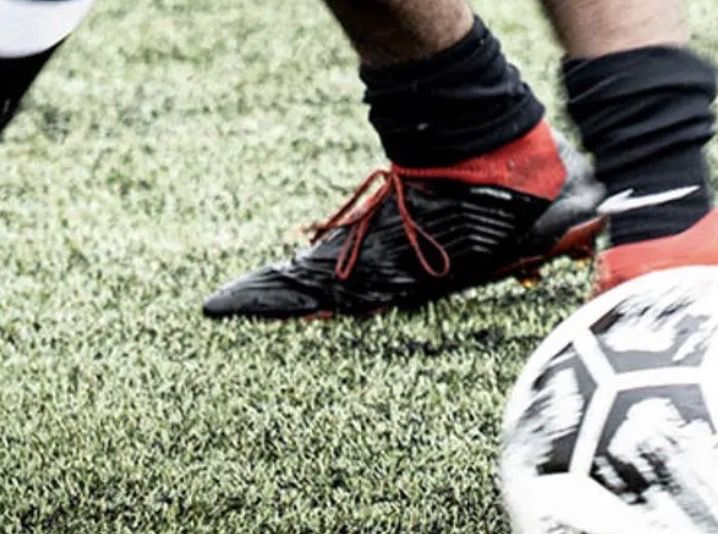 Close up of football player's boots in motion kicking a ball.