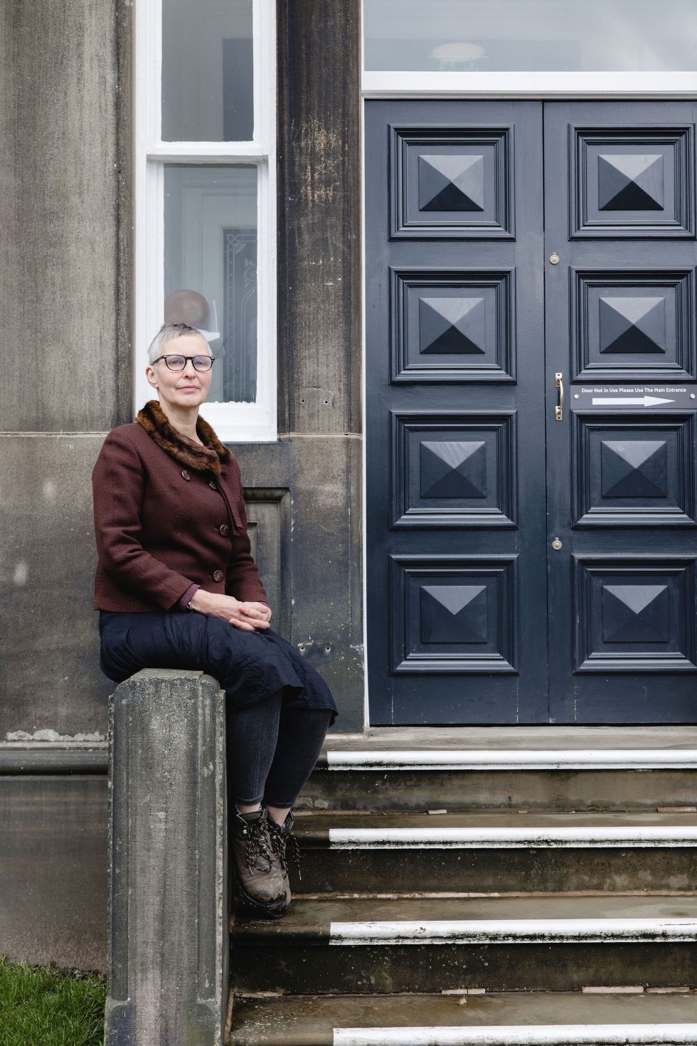 Marjan Wouda seated beside the steps outside The Whitaker Museum. Image Christina Davies, Fish 2 Photography.